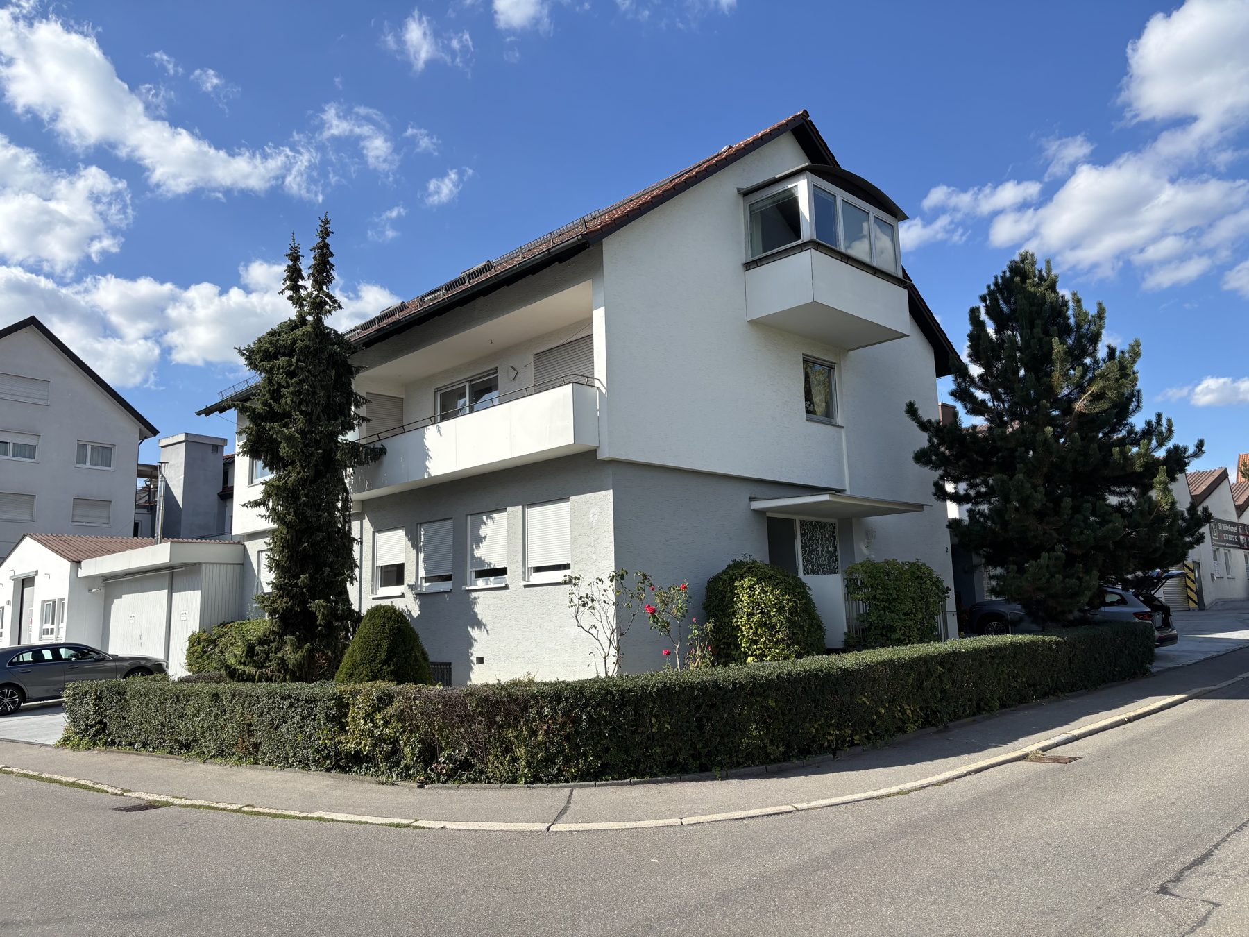 Das Bürogebäude in der Würbenthaler Straße 2, 71065 Sindelfingen: heller Putzbau in Ecklage mit Hecke und Bäumen